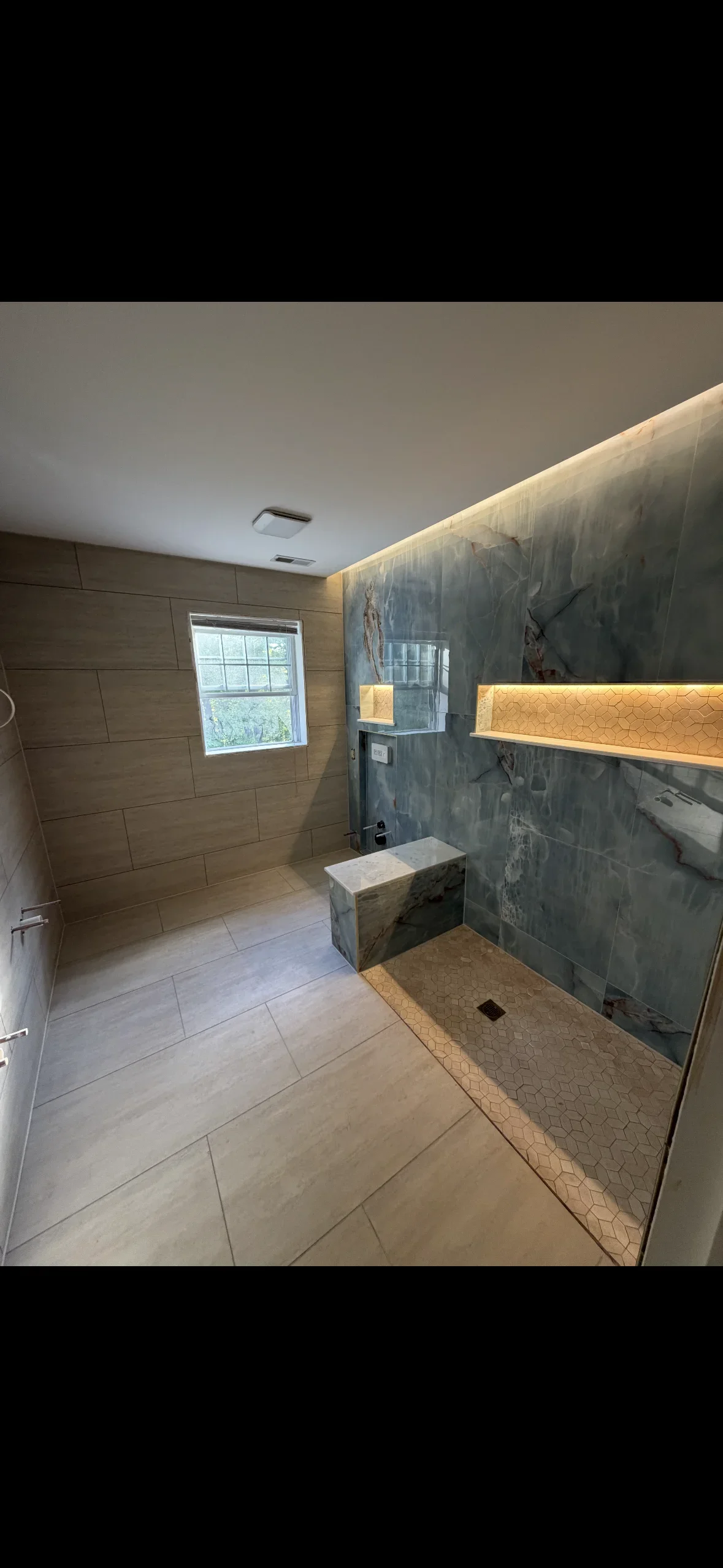 Modern master bathroom with slate tile shower, wood paneling, and warm accent lighting