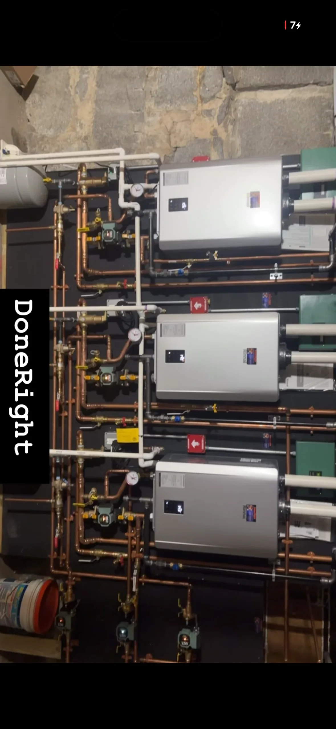 Three white tankless water heaters with copper piping and brass fittings installed vertically