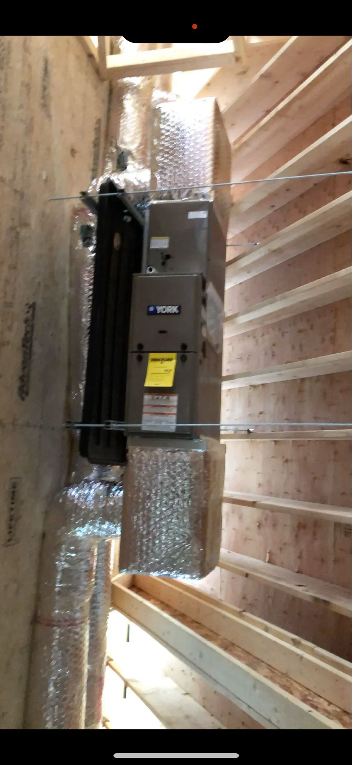 York HVAC unit installed in wooden framed cavity with insulation wrap and cable supports
