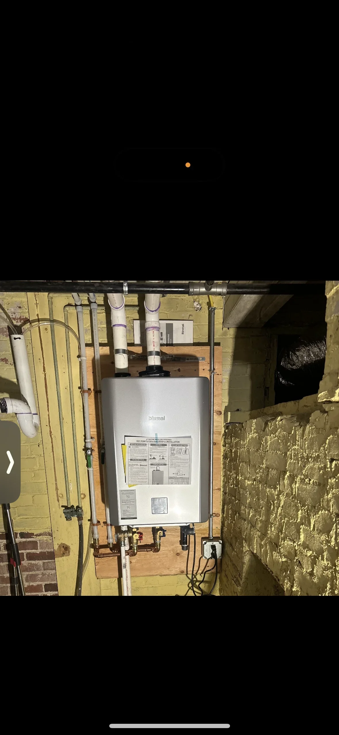 Installed Rinnai tankless water heater with PVC venting and copper piping connections in basement