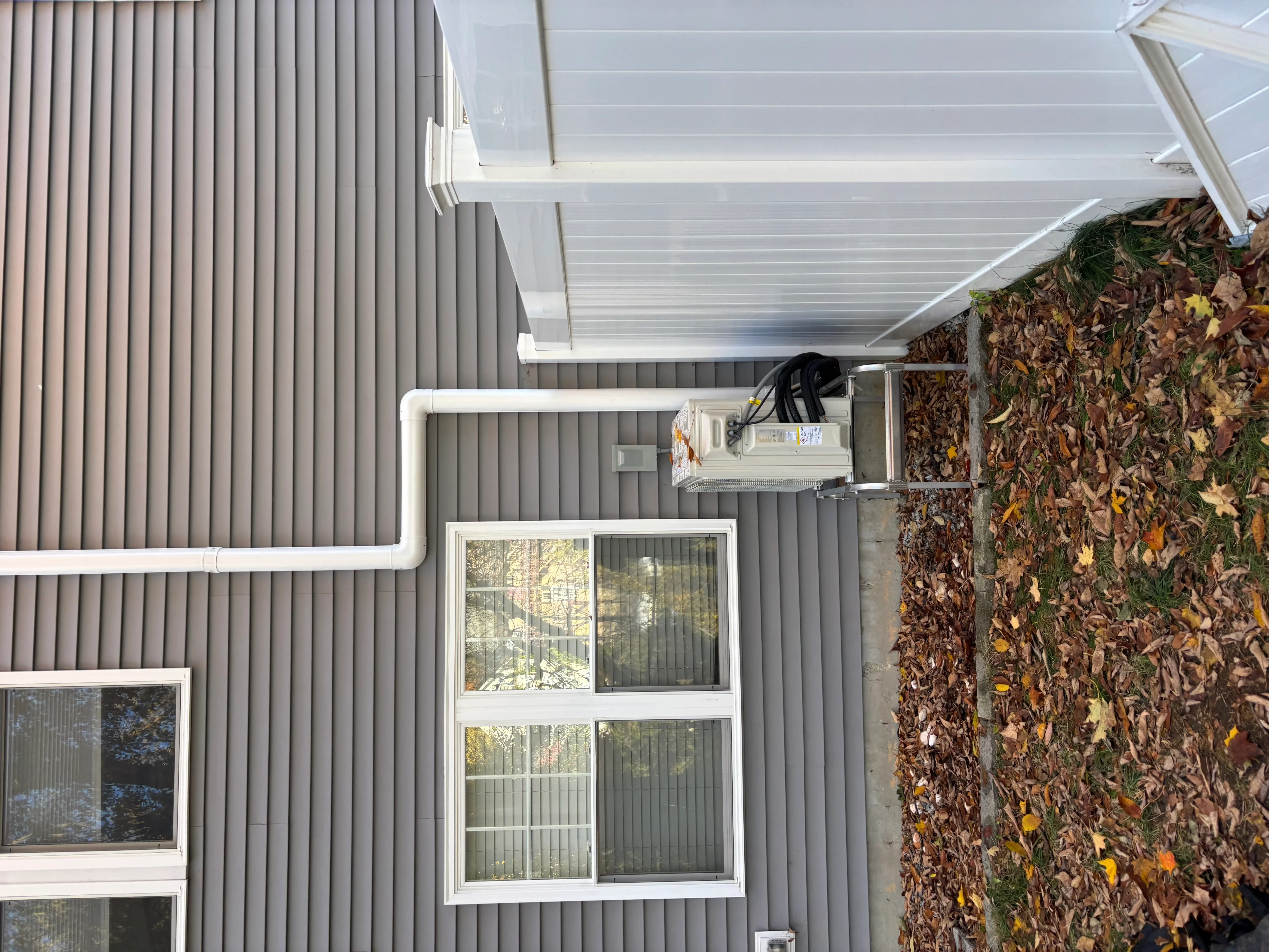 White gutter and downspout system installed on gray metal-sided residential building
